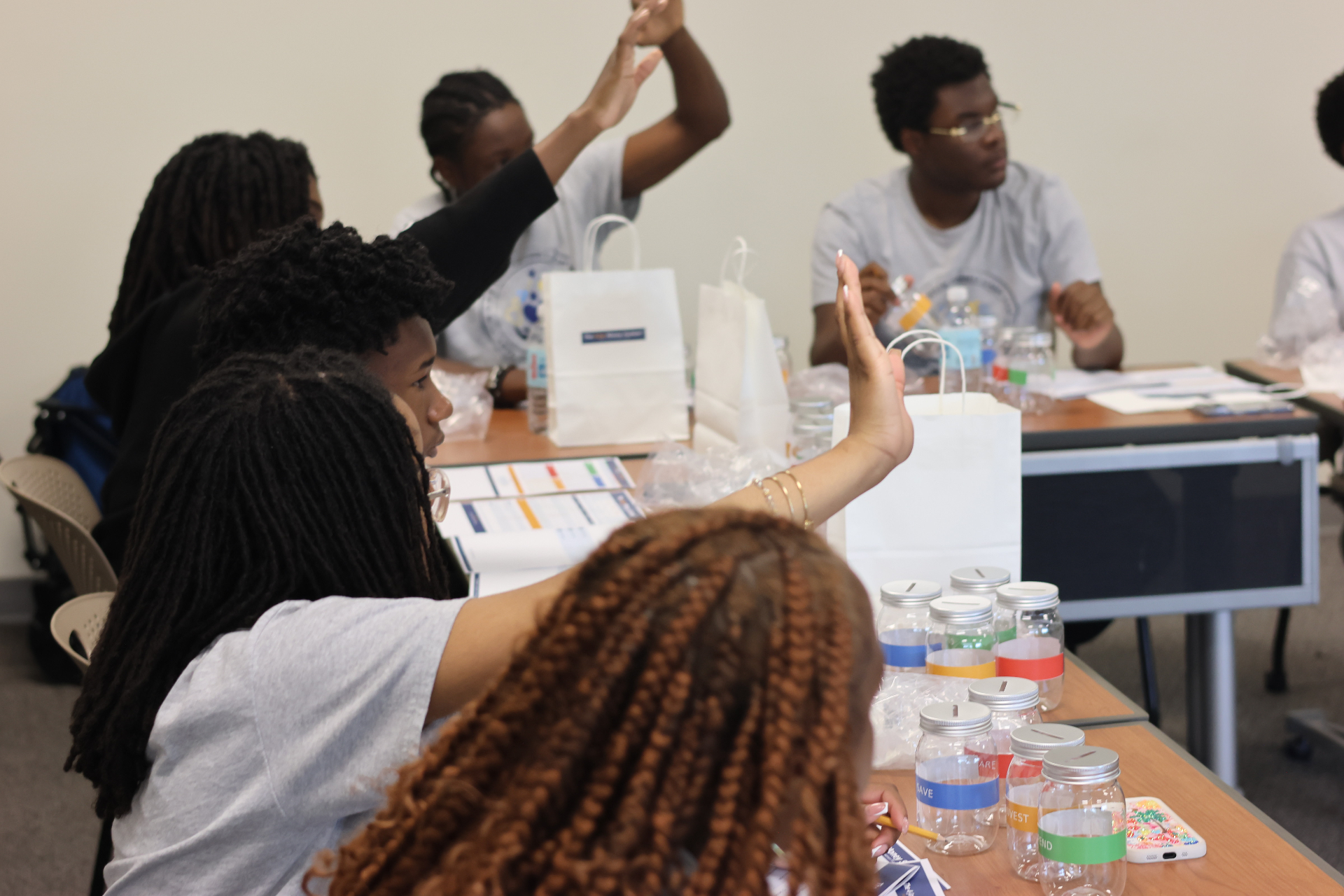 Youth participants raising hands during a facilitated 4-Jar Money System™ discussion